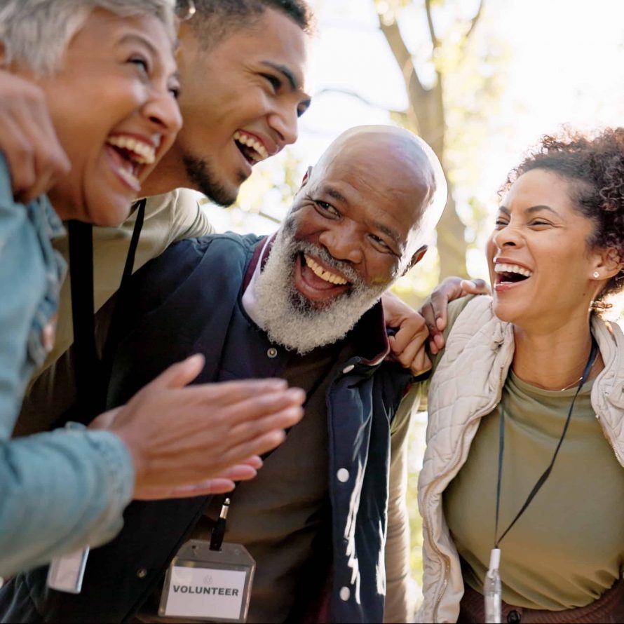 Huddle, excited and group of people outdoor with collaboration, teamwork and solidarity for charity work. Hug, smile and volunteer or ngo in park with cooperation, community and together for support